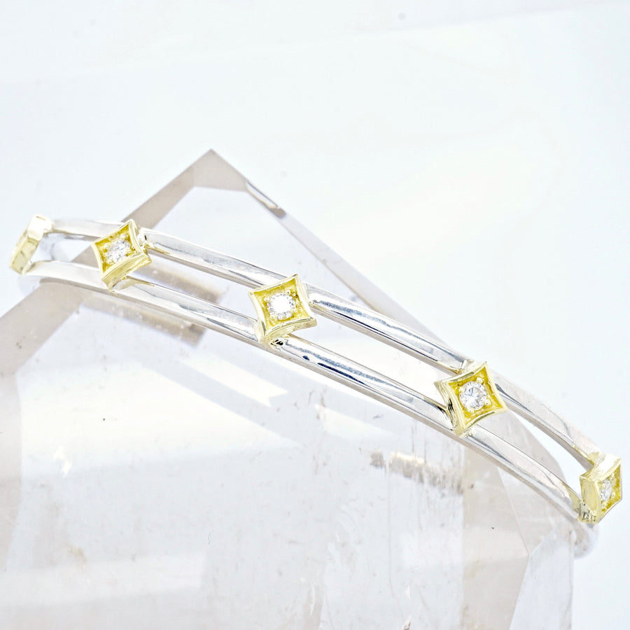 An open cuff, two-tone bangle in sterling silver with 18k gold diamond stars.